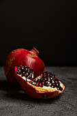 A bright pomegranate with juicy seeds against a dark background. The rich red tones and glossy texture make it ideal for nutrition, health or natural lifestyle themes.