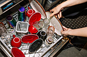 Colourful coffee cups and saucers are placed in the dishwasher. Shades of red and iridescent colours create a vibrant scene that emphasises cleanliness in a cosy café environment.