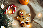 Ein fröhlicher Lebkuchenmann, umgeben von einer Zuckerstange, Orange und warm leuchtenden Lichtern - perfekt, um die festliche Jahreszeit mit Süße und Stil zu feiern