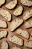 Rustikale, handwerklich hergestellte Brotscheiben auf einem strukturierten braunen Hintergrund Die goldene Kruste und die luftige Krume schaffen eine einladende Szene, die die natürliche Schönheit des Brotes hervorhebt