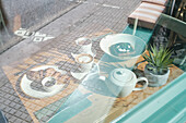 Through a sunlit coffee window, you can see a fresh pastry, toast with toppings and a warm cup of tea on a table The cosy surroundings invite you to relax and enjoy yourself