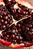 A vibrant close-up of a fresh pomegranate that has been sliced open to reveal its juicy, ruby-red seeds. The image captures the texture and rich colour of the fruit and is ideal for culinary themes.