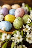 Pastel-coloured Easter eggs lie next to delicate white flowers, creating a charming and festive arrangement that is perfect for spring celebrations and decorations.