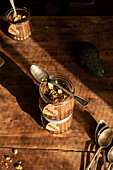 A beautifully presented vegan chocolate mousse with avocado slices and crushed nuts, served in a rustic glass jar on a wooden table, illuminated by natural sunlight.