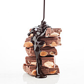 A delicious stack of chocolate bars filled with almonds is covered in rich, melted chocolate. The picture captures the pleasure of this delicious treat in true detail.