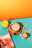 Top view of a lively breakfast with a bowl of muesli with milk, a glass of orange juice and a cup of coffee on a two-coloured table.