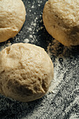 Close-up of fresh, raw dough balls resting on a floured surface. You can see the texture and soft consistency of the dough in detail, ideal for baking themes.