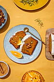 Slices of carrot cake with rich cream cheese icing and garnished with walnuts and rosemary on a linen background A perfect dessert set-up with bright colours
