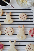 Top view of biscuits in the shape of an Easter bunny, painted with hibiscus tea and placed on a cooling rack. The image captures the fine details of the natural pink colour tones that decorate each biscuit.