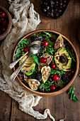 A colourful salad with fresh figs, avocado, cherries and blackberries on a bed of rocket, sprinkled with almonds in a wooden bowl on a rustic wooden table.