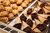 Eine fesselnde Auslage mit Gebäck und schokoladengefüllten Tüten im Schaufenster einer Bäckerei Das Bild zeigt die Beschaffenheit und Attraktivität frischer Backwaren und lockt Kunden an