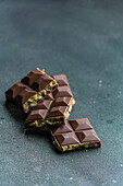 Homemade milk chocolate bar filled with pistachio paste, also known as Dubai chocolate, on a dark textured background.