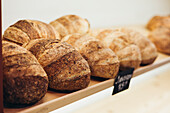 A cosy bakery shelf showcases freshly baked, crusty, artisan loaves of bread and captures the warmth and aroma of a traditional bakery, perfect for food and culinary themes