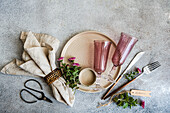 A rustic autumn table with linen napkins, pink glasses, old scissors and fresh flowers. The elegant arrangement conveys a cosy, seasonal atmosphere