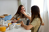Ein lesbisches Paar frühstückt fröhlich und tauscht sich an einem hellen, luftigen Tisch aus Das Bild strahlt Liebe und Kameradschaft in einer warmen Morgenstimmung aus