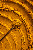 A vibrant close-up of golden curry powder, showing the textured surface with swirling patterns This aromatic spice is perfect as an ingredient for cauliflower curry soup and more