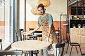 A friendly coffee house employee organises the tables and creates a welcoming atmosphere for the guests.