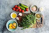 A colourful mix of healthy ingredients for lunch, including fresh rocket, chopped oregano, cherry tomatoes, cucumber, Himalayan salt, red onion, lemon and organic olive oil.