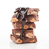 A stack of chocolate bars with almonds, covered in rich, shiny melted chocolate, against a white background. Perfect for illustrating desserts or sweet cravings.