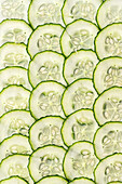 Ein lebhaftes Arrangement frischer Gurkenscheiben, das ihre grünen Ränder und komplizierten Samenmuster zur Geltung bringt. Ideal zur Veranschaulichung von Frische und gesunden Ernährungskonzepten.