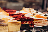 A delicious display of various cakes and pastries, including red velvet and cheesecake, in the window of a patisserie Perfect treat for dessert lovers