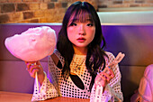 Asian Gen Z girl enjoys a fun day of candyfloss and tickets The lively environment reflects her enthusiasm and youthful spirit
