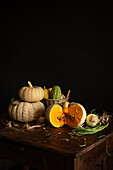 A rustic still life with pumpkins, root vegetables and a basket of pumpkins on a wooden table. The warm colours and natural textures are reminiscent of an autumnal harvest environment.
