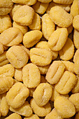 Top view of uncooked, frozen gnocchi, dusted with flour, densely packed and with clear indentations, ideal for Italian cuisine themes.