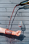 A visually striking composition in which red wine is poured into a glass through a tattooed arm, creating a surreal and artistic effect. A bold and unconventional concept for restaurant branding and marketing.