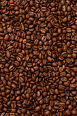 A detailed view of freshly roasted coffee beans that showcases their rich brown texture - perfect for illustrating themes such as coffee, energy and morning rituals