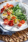 Ein lebhaftes Keto-Mittagessen mit gekochten Eiern, frischem Rucola, Kirschtomaten, grünen Erbsen aus der Dose und gekeimten grünen Bohnen, alles mit Balsamico-Sauce angerichtet.