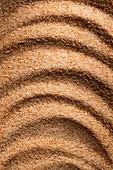 Textured brown sugar shot at close range, with natural shadow lines, ideal for culinary and design backgrounds.
