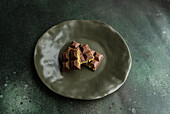 Top view of a homemade milk chocolate bar filled with rich pistachio paste, presented on a textured green plate. It is often referred to as Dubai chocolate.