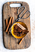 Top view of aromatic aniseed stars and cinnamon sticks, elegantly arranged with old scissors on a rustic wooden board, beautifully complemented by soft, natural light.