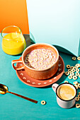A lively breakfast scene with a bowl of cereal with milk and a glass of orange juice against a colourful background.