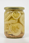 A jar with sliced gherkins pickled in vinegar and mustard seeds on the bottom. Perfect for demonstrating food preservation or homemade pickling.