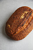 Top view of a freshly baked sourdough bread with a dark, crispy crust on a textured background.