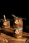 Vegan chocolate avocado mousse in glasses, decorated with love tags and pistachios, captured in warm sunlight against a rustic wooden backdrop.
