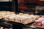 A delightful selection of pastries elegantly displayed in a shop window, showcasing fluffy meringues in a variety of colours - perfect for a bakery or patisserie theme