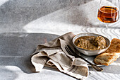 A bowl of satsivi, the famous Georgian chicken in walnut sauce, paired with freshly baked bread and a glass of rare amber wine, elegantly presented on a minimalist table.