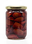 A clear glass jar filled with preserved plums in a rich, golden syrup. The jar is sealed with a golden metal lid that shows off the preserved fruit. Ideal for preserves, food concepts.