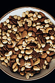 A close-up of a bowl containing a selection of nuts, including cashews, almonds, hazelnuts and pecans - perfect for healthy snacks