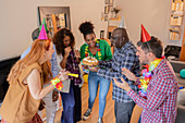 A group of friends celebrate a birthday indoors with smiles and lively party decorations. They gather around a cake and create a cheerful atmosphere.