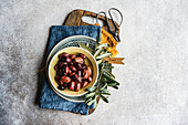 Top view of a rustic bowl of Greek grilled olives on a wooden board with fresh olive branches, ideal for a Mediterranean culinary ambience.