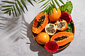 Exotic tropical fruits, passion fruit and dragon fruit, ripe papayas. on a bamboo tray with green leaves, stone background
