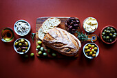 Selection of olive products, including Kalamata olive sourdough bread, green olive dip, olive oil, dairy-free olive spread, Sicilian olives and marinated green and black olives.