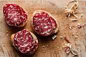 Italian salami slices on homemade bread on a wooden cutting board
