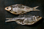 Pile of sun-dried sea fish Sea bream on a dark textured background. Salty traditional starter. Seafood background