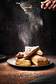 Apple pockets with icing sugar on a wooden surface