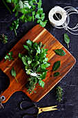 Preparation of homemade bouquet garni with parsley, bay leaves, sage, rosemary and celery leaves.